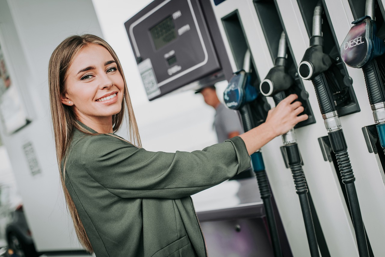 Happy lady taking the petrol pump nozzle