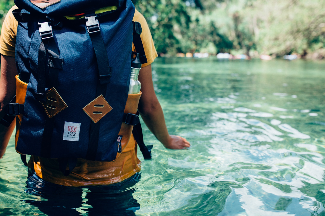Walking through water with a packed hiking bag
