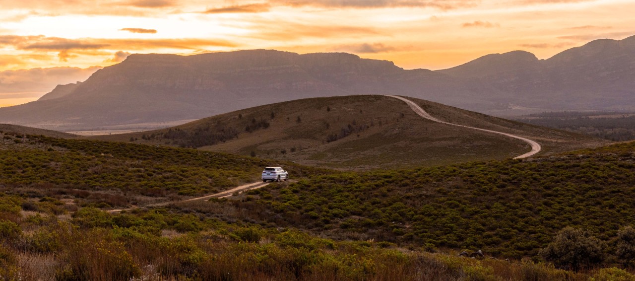 Mitsubishi Outlander PHEV driving on a windy road through a beautiful valley.